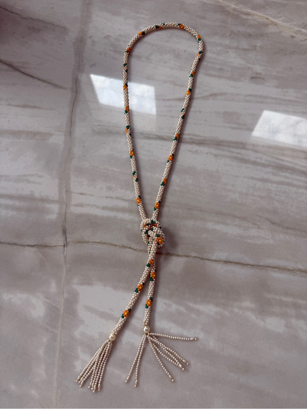 Vintage hand-beaded lariat necklace featuring a cream-colored seed bead rope